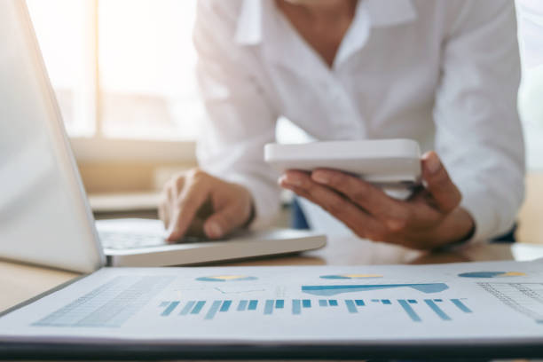istock Female accountant calculations and analyzing financial graph data with calculator and laptop Business, Financing, Accounting, Doing finance, Economy, Savings Banking Concept 872412306