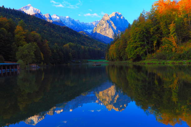 Riessersee alpine turquoise lake with reflection at gold colored sunrise, with Zugspitze, Waxenstein and Alpspitze view– dramatic landscape in Bavarian alps, Germany - Majestic alpine landscape in autumn, Snowcapped mountains – Garmisch, Bavaria, Germany lago alpino de turquesa riessersee, con reflejo al amanecer color oro, con el zugspitze, waxenstein y alpspitze vista espectacular paisaje en los alpes bávaros, alemania - majestuoso paisaje alpino en las montañas nevadas, otoño – garmisch, baviera, alemania