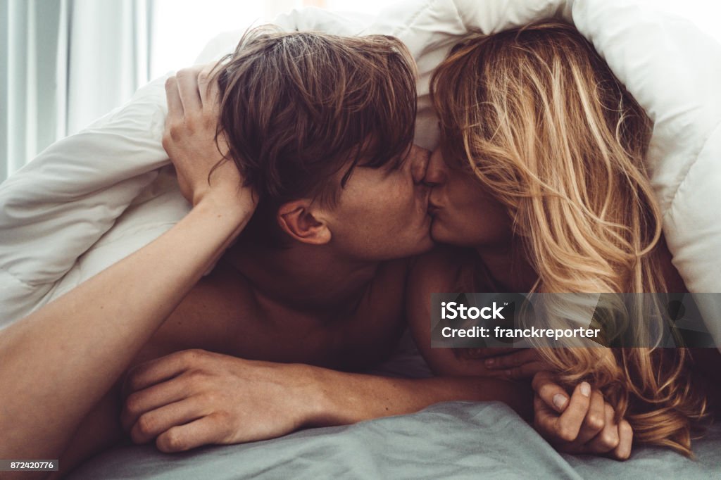 pareja besándose en el dormitorio - Foto de stock de Parejas libre de derechos