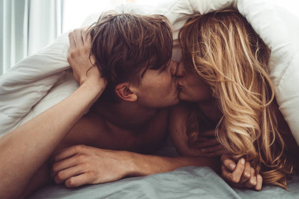 pareja besándose en el dormitorio - sexo y reproducción fotografías e imágenes de stock