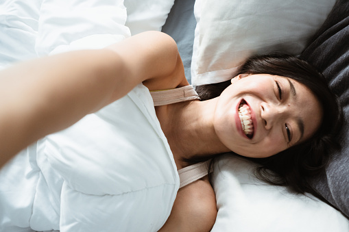 chinese woman taking a selfie on the bed