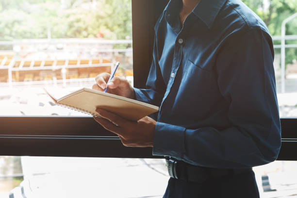 istock Close up shot smart businessman writing his idea in notebook near window 872436848