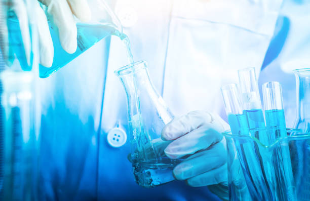 istock Blue drop into glass beaker with flask and science laboratory background 872437468