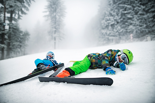 Little skiers lying on slope after crashing