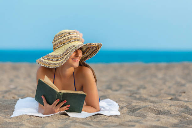istock Young woman reading book on Beach 872444964