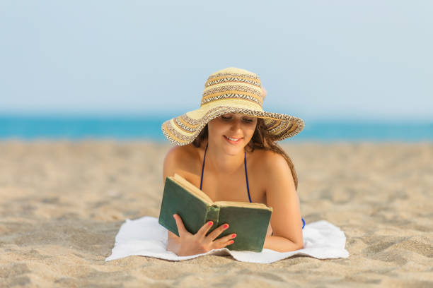 istock Young woman reading book on Beach 872445114