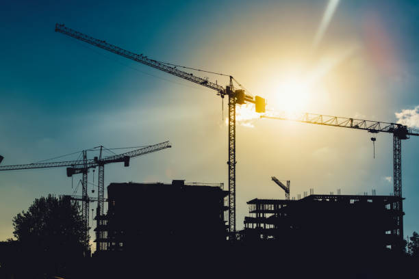 istock Silhouette of tower cranes on industrial construction site 872445156