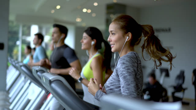 People at a fitness center running on the treadmills looking determined