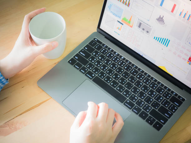 istock white hand with blue cloth hold cup and search data and check finance graph from internet for her business with laptop on wooden table background 872460864