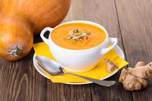 pumpkin cream soup with ginger on a wooden background