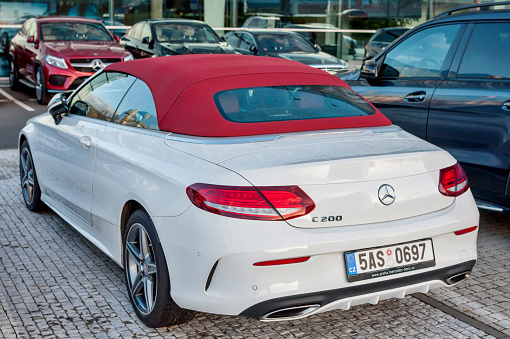 PRAGUE, THE CZECH REP., NOVEMBER 27, 2016: Rear view of Luxury car white cabrio Mercedes-Benz C200 with red roof. Car parking in front of car store Daimler