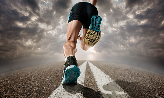 The close up feet and back of man running and training on running track. Advertising image about sport and healthy lifestyle