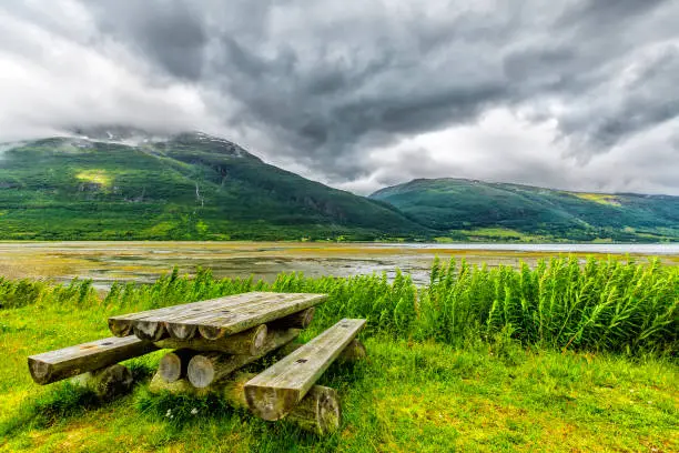 Photo of Wooden table and benches on the bay of norwegian fijord