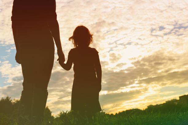 silhouette of father and daughter holding hands at sunset silhouette of father and daughter holding hands at sunset sky kid holding fathers hand stock pictures, royalty-free photos & images