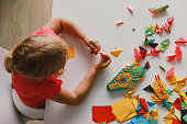 little girl making origami crafts with paper