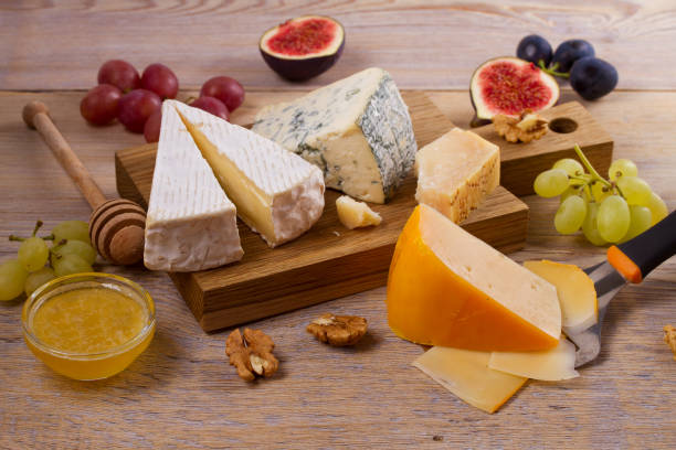 istock Cheese plate. Various types of cheese with grapes, honey, figs and nuts on rustic wooden table 872484212