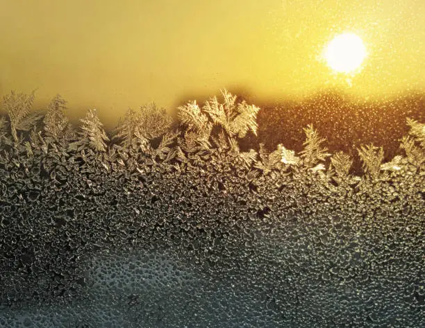 Natural ice pattern and bright sunlight on winter window glass