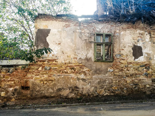 istock Old abandoned and ruined house with smashed window and green shutters 872501282