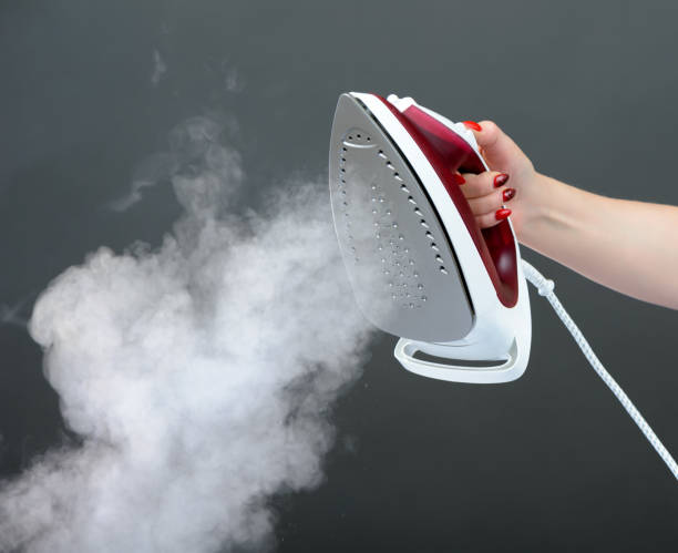istock Iron with steam on dark grey background 872508960