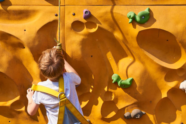 istock Child climbing a rock wall outdoor - bouldering 872518158