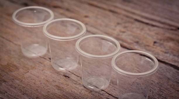 istock Empty clear color plastic cup on Top wooden table with detailed textured look clean, soft and warm , use as background for product display. 872518558