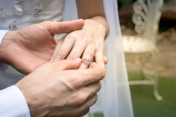 istock Hand of the groom wears a wedding ring bride 872518754