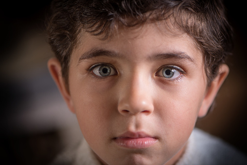Close viewing portrait of cute young boy with expressive eyes.