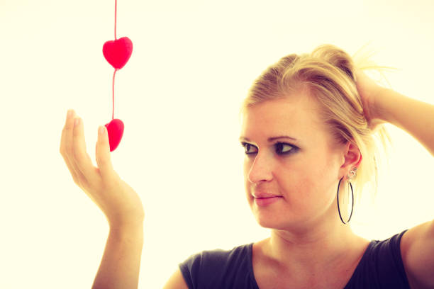 Portrait of a young woman posing with a heart against a gray background