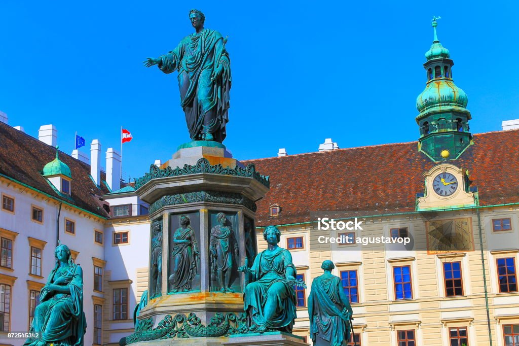 Beautiful monument to Franz Joseph I of Austria on Amalienburg - Vienna Cityscape panorama, with  impressive rococo and reinassance building architecture and urban skyline at clear sky – Austrian and Euro flags - Vienna , Austria Austria Stock Photo