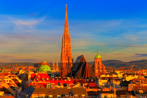 Above Beautiful Vienna Cityscape panorama, with St. Stephen's Cathedral, impressive building architecture and urban skyline at dramatic gold colored sunrise – Vienna , Austria