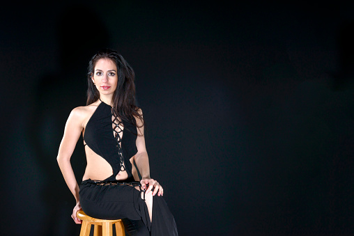 Beautiful young women sitting on wooden chair on black background