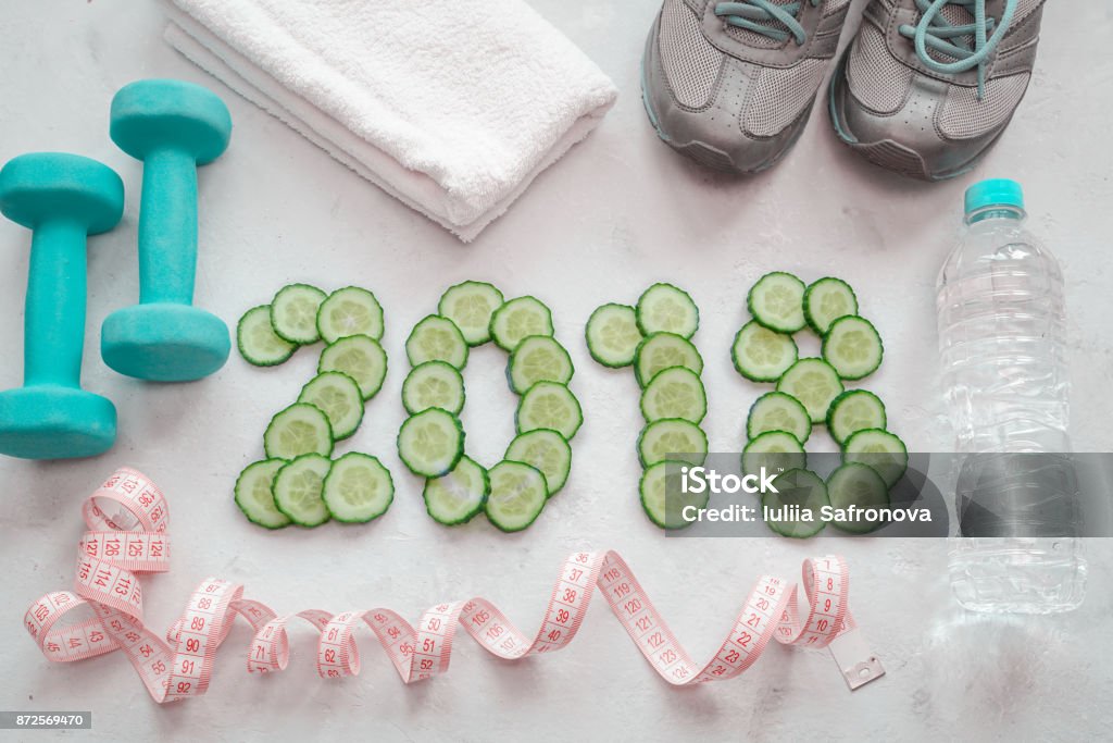 Turnschuhe, Handtuch, Wasser und Hanteln. Gurke in Scheiben geschnitten-Symbol für das neue Jahr. - Lizenzfrei 2018 Stock-Foto