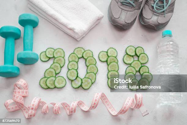 Photo libre de droit de Chaussures De Sport Serviette Eau Et Haltères Concombre Tranché Le Symbole De La Nouvelle Année banque d'images et plus d'images libres de droit de 2018