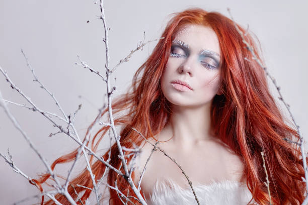 Redhead Girl With Long Hair A Face Covered With Snow With Frost White  Eyebrows And Eyelashes In Frost A Tree Branch Covered With Snow Snow Queen  And Winter Winter Makeup Woman Face