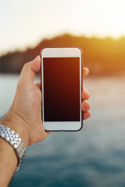 istock Male hand holding blank mobile phone outdoors 872576014