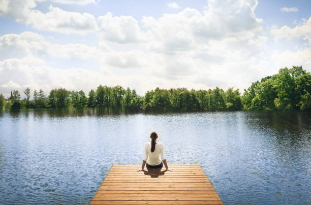 istock Woman relaxes on lake pier 872576214