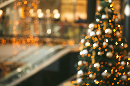 Festive blurred backdrop of mall decorated for Christmas. Blurred man on escalator