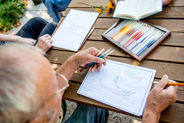istock Senior Man Coloring a Coloring Sketch 872586924
