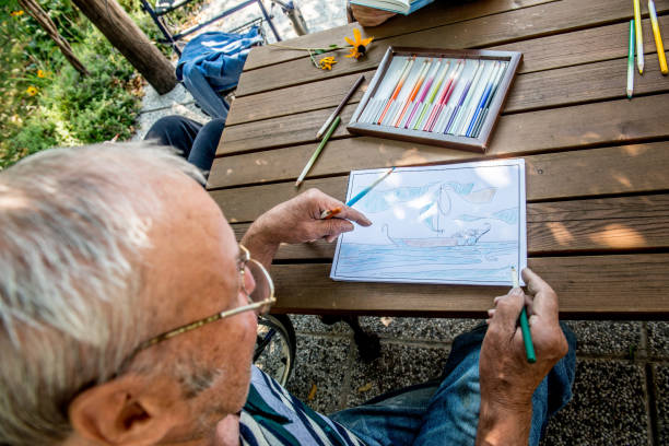istock Senior Man Coloring a Coloring Sketch 872587066