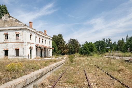 derelict former raiway station with rusty rails covered with grass in Agreda, Spain