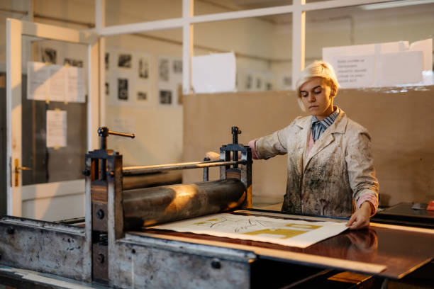 istock Artist is producing artwork in her workshop with printing press and etching metal plate 872590416