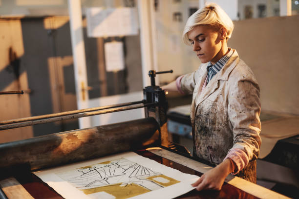 istock Printing and etching - female artist working with printing press 872590814