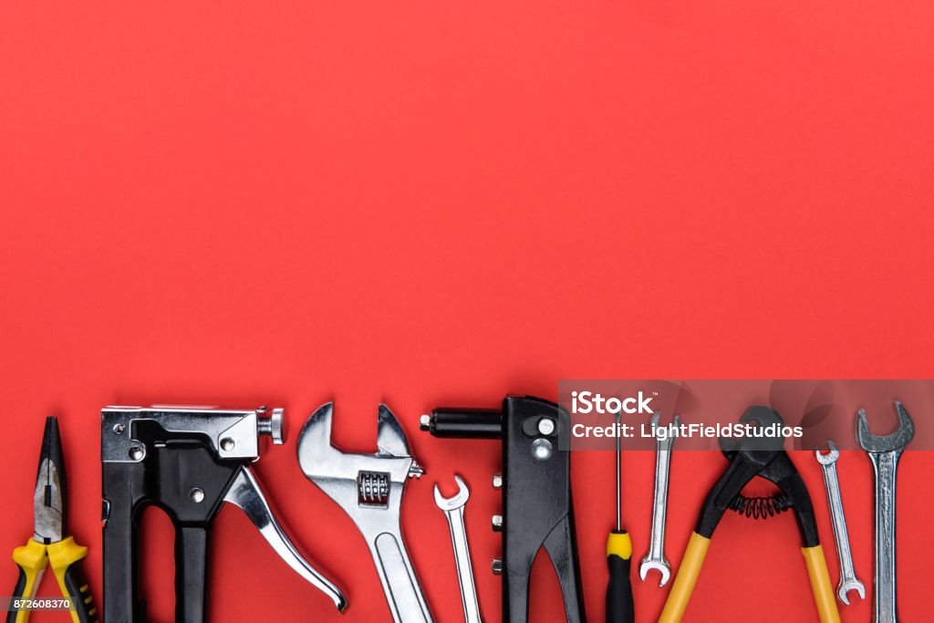 different reparement tools Top view shot of different reparement tools - wrenches, pliers, industrial stapler, isolated on red Work Tool Stock Photo