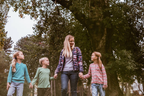 istock Mother walking and talking with her children in public park 872612224