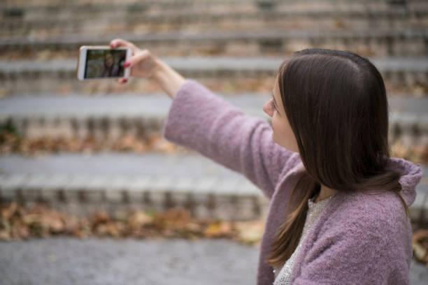 istock Young woman taking selfies at the park 872617520