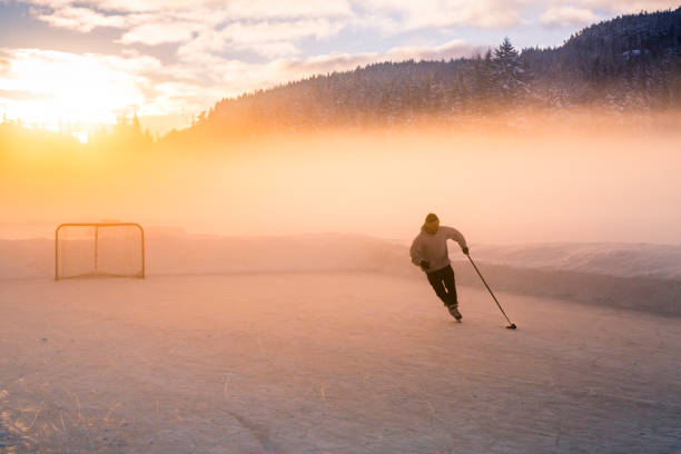 young man playing hockey on frozen lake. - winter lake snow fog imagens e fotografias de stock