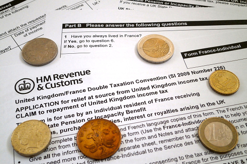 London, England - May 25 2017: United Kingdom/France Double Taxation Convention with some coins from both countries.