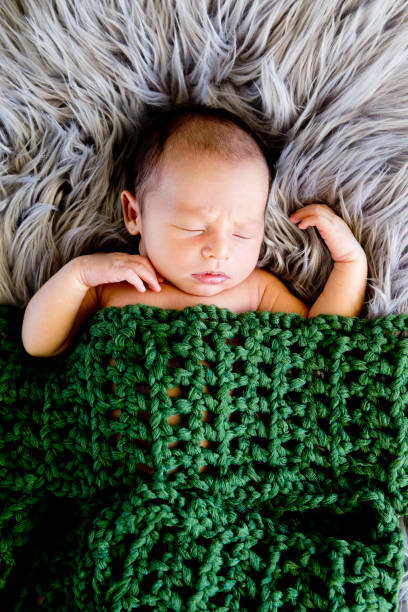 istock New Baby Boy sleeping covered by dark olive green crotcheted blanket 872625420