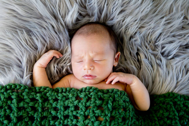 istock New Baby Boy sleeping covered by dark olive green crotcheted blanket 872625428
