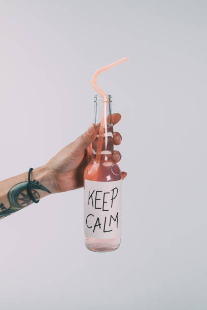 close-up partial view of hand holding bottle of alcohol beverage with inscription keep calm on label